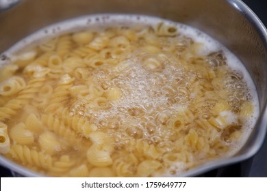 Cooking Pasta In Pot Of Boiling Water On Stove In Kitchen. Italian Pasta. Macaroni Of Various Varieties In Very Hot Voda. Water Boils And Spaghetti Noodles For Cooking Italian Pasta