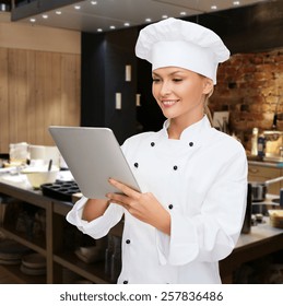 Cooking, People, Technology And Food Concept - Smiling Female Chef, Cook Or Baker With Tablet Pc Computer Over Restaurant Kitchen Background