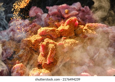 Cooking Pilaf On A Fire. Meat With Carrot And Spices Is Cooking In Cauldron On Fire With Smoke. Shallow Depth Of Field