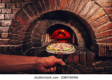 Cooking Pizza In An Italian Stone Oven. Chef Puts The Pizza In The Oven.