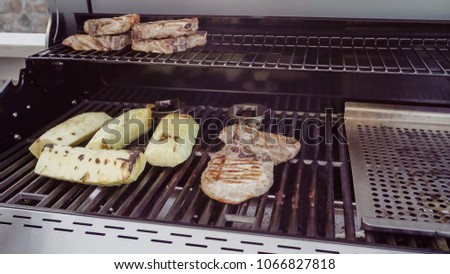 Cooking pork chops with pineapples on gas grill in the Summer.