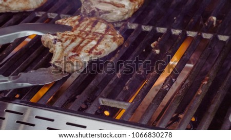 Cooking pork chops with pineapples on gas grill in the Summer.