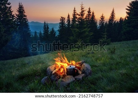 Cooking pot near campfire in picturesque place in the mountains. Living in wilderness.
