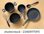 Cooking pots, frying pan and kitchen utensils on beige background