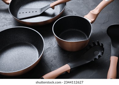 Cooking pots, frying pan and kitchen utensils on dark background, closeup