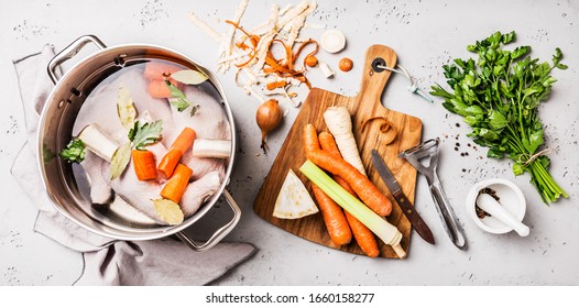 Cooking - Preparing Chicken Stock (broth Or Bouillon) With Vegetables In A Pot. Kitchen - Grey Concrete Worktop Scenery From Above (top View, Flat Lay).