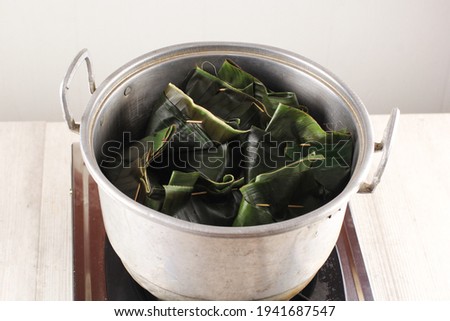 Cooking Process: Asian Female Hand  Open Steaming Lid with "Pepes Ayam" Inside with Natural Smoke. Pepes Ayam is SPice Chicken with Banana Leaf Wrapped