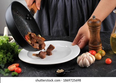 Cooking Process, Asian WOman Chef Put Grilled Wagyu Fatty Saikoro Cubed Dice Beef Steak With Barbeque Sauce On Black Pan To White  Plate