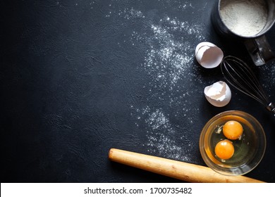 Cooking process.Flour, Eggs, Yolk, Shell,
whisk,rolling pin.Flour scattered on a black concrete background.
 - Powered by Shutterstock