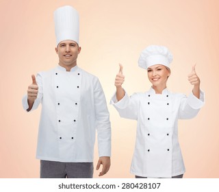 cooking, profession, gesture, teamwork and people concept - happy chefs or cooks couple showing thumbs up over beige background - Powered by Shutterstock