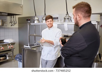 cooking, profession and people concept - happy male chef and cook having coffee break and talking at restaurant kitchen - Powered by Shutterstock