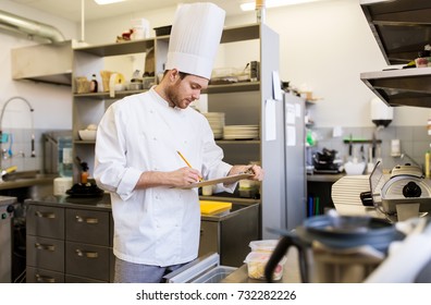 Cooking, Profession And People Concept - Male Chef Cook With Clipboard Doing Inventory Of Restaurant Kitchen Fridge