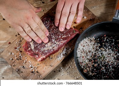 Cooking Raw Steak With Sea Salt And Pepper By Chef Hand. Flank Beef Meat. Flat Top View, Overhead.