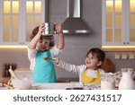 Cooking recipe. Cute children sieving flour at table in kitchen