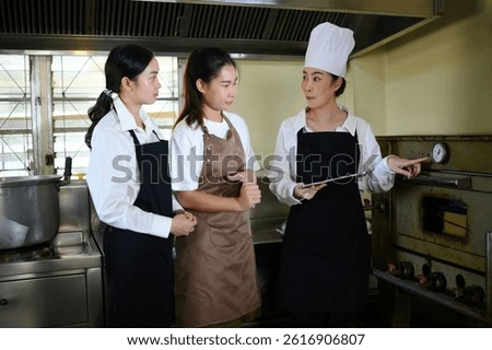 Cooking school instructor explaining oven temperature control to students