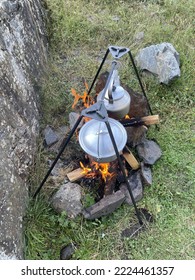 Cooking Soup In A Saucepan And Boiling Water In A Kettle On An Open Fire In The Forest. Top View