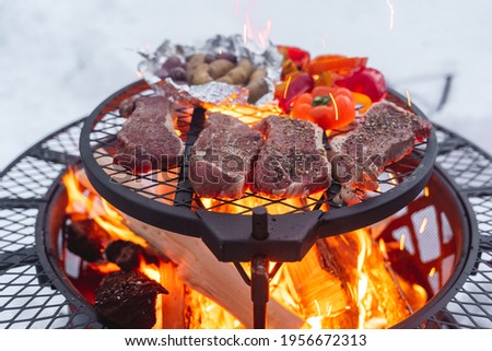Cooking steak and food on a firepit outside in the snow in the woods of Fairbanks Alaska