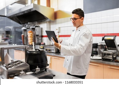 cooking, technology and people concept - happy male chef cook with tablet pc computer at kebab shop - Powered by Shutterstock