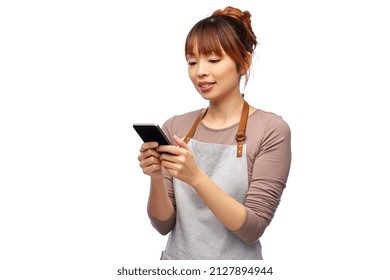 cooking, technology and people concept - happy smiling female chef or waitress in apron showing smartphone with empty screen over white background