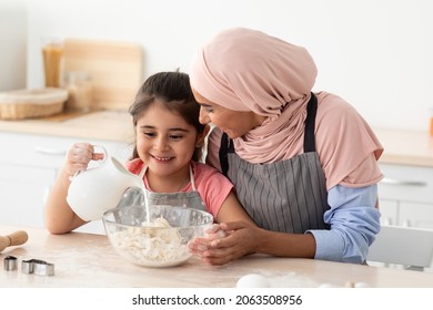 Cooking Together. Muslim Mother Baking With Her Little Daughter In Kitchen, Cute Female Child Preparing Dough For Cookies With Young Islamic Mom In Hijab, Adding Milk To Bowl, Closeup Shot - Powered by Shutterstock