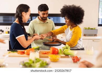 Cooking together, young diverse friends preparing meal in modern kitchen, enjoying time. fun, domestic - Powered by Shutterstock