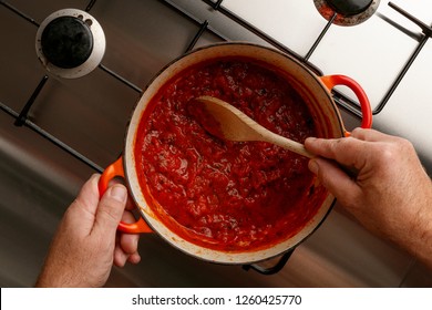 Cooking A Traditional Gormet Tomato Sauce And Wooden Spoon, On A Stainless Steal Hob, Shot From Above