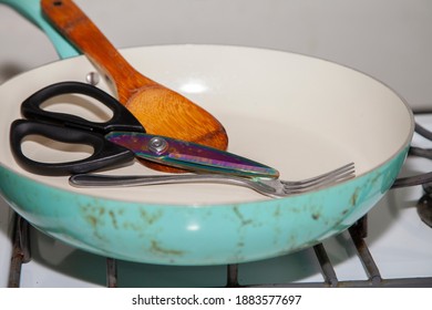 Cooking Utensils, A Wooden Spoon, Kitchen Shears, And A Fork In A Frying Pan