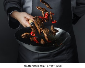 Cooking In Wok Pan - Sliced Beef Meat And Chilli Pepper On Black Background, Professional Restaurant And Hotel Service Food Concept.