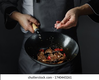 Cooking In Wok Pan - Sliced Beef Meat And Chilli Pepper On Black Background, Professional Restaurant And Hotel Service Food Concept.