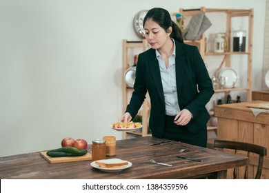 Cooking Woman Employee In Kitchen With Wooden Table. Young Elegant Wife With Love Prepared Breakfast For Husband Before Work. Single Asian Mom Set Up Healthy Meal At Home In Early Morning For Child