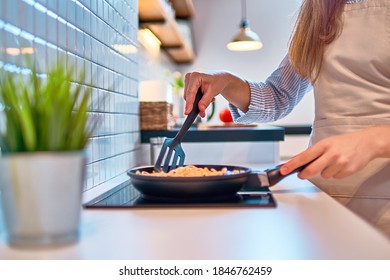 Cooking woman housewife preparing food in a frying pan on the stove for delicious dinner at modern loft style kitchen                 - Powered by Shutterstock