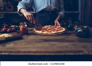 Cook's Hands Making Homemade Pizza On The Table. Pizza With Ingredients. Tomatoes, Garlic, Parsley, Pepper, And Parmesan Cheese On Dark Wooden Background. Food, Family And People Concept.