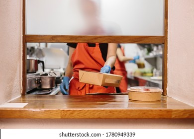 Cooks in a restaurant preparing takeaway food. The containers used are compostable. - Powered by Shutterstock