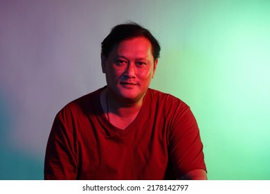 The Cool Adult Asian Man On The Blue Background Under The Color Gel Lighting. 