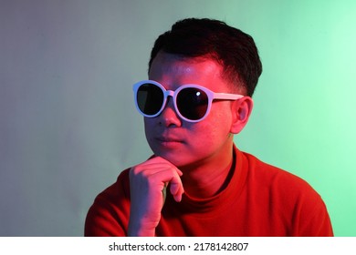 The Cool Adult Asian Man On The Blue Background Under The Color Gel Lighting. 