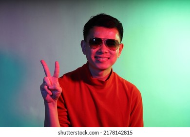 The Cool Adult Asian Man On The Blue Background Under The Color Gel Lighting. 