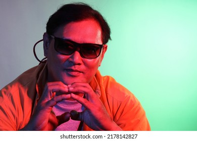 The Cool Adult Asian Man On The Blue Background Under The Color Gel Lighting. 