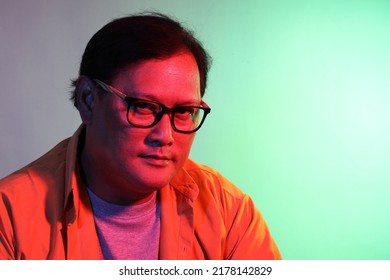 The Cool Adult Asian Man On The Blue Background Under The Color Gel Lighting. 