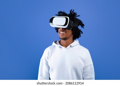 Cool African American teen guy wearing VR headset, using virtual reality for entertainment on blue studio background, copy space. Funky black youth exploring cyberspace. Futuristic technologies - Powered by Shutterstock