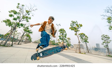 Cool Asian guy skating on longboard skate at park on summer holiday vacation. Stylish young man enjoy and fun urban active lifestyle practicing outdoor sport skateboarding on city street at sunset. - Powered by Shutterstock