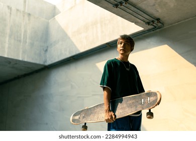 Cool Asian guy skating on longboard skate at park on summer holiday vacation. Stylish young man enjoy and fun urban active lifestyle practicing outdoor sport skateboarding on city street at sunset. - Powered by Shutterstock