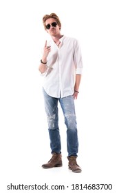 Cool Attitude Young Guy In Stylish Clothes With Sunglasses Pointing Finger Up Above. Full Length Portrait Isolated On White Background. 