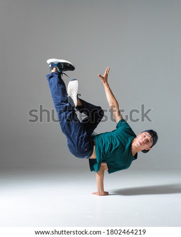 Cool b-boy dancing breakdance on the floor in studio isolated on gray background. Breakdancing school poster