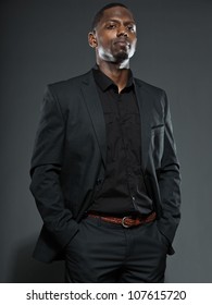 Cool Black American Man In Dark Suit. Studio Fashion Shot Isolated On Grey Background.