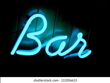 A Cool Blue Lit Neon Bar Sign On A Teak Wood Paneled Wall