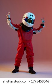 Cool boy child racer in helmet with raised hands with peace gesture, standing in neon light. Kart racing school poster