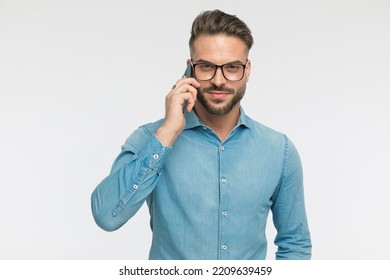 Cool Casual Man Talking On The Phone, Looking At The Camera And Wearing Eyeglasses On Gray Background