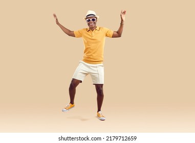 Cool cheerful african american man funny rejoicing and dancing isolated on beige background. Emotional dark-skinned man in stylish summer clothes having fun on vacation. Fun concept. Full length. - Shutterstock ID 2179712659