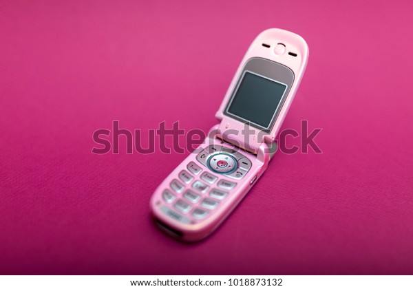 Cool and classic pink retro flip cell or\
mobile phone isolated against a red\
background