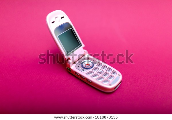 Cool and classic pink retro flip cell or
mobile phone isolated against a red
background